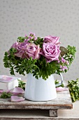Bouquet of scented roses and pelargoniums in enamel jug