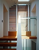 Modern stairwell with slats in front of ceiling-height window and wooden stair treads