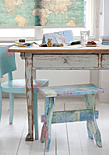 Kitchen table with flaking paint and painted footstool on white wood floor