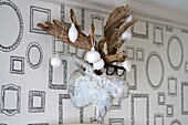 Wooden antler decoration with glasses and white baubles on wall with picture frame wallpaper