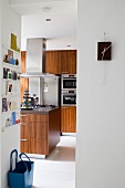 Blick durch raumhohen Durchgang in moderne Küche mit Holzfronten