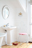 Light-coloured bathroom with white wooden panels and pillar washbasin