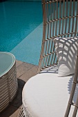 Ausschnitt eines Stuhls mit weißem Sitzpolster vor Pool