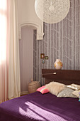 A designer lamp above a double bed in the corner of a bedroom with a traditional atmosphere