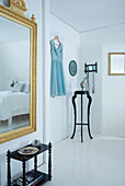 Weißes Schlafzimmer mit goldgerahmtem Spiegel und schwarzer Konsole