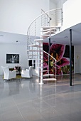 A simple spiral staircase connecting an open-plan living area with a polished stone floor with a gallery