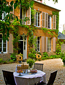 Idyllic terrace with gravel floor in front of rural house with shutters