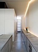 Langes, graues Sideboard mit Kücheneinbaugerät und freistehender Küchenblock im Betonlook