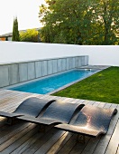 Pool and wooden deck with loungers in garden