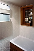 Corner of white-tiled bathroom and bathtub