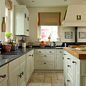 Country kitchen with light-coloured cupboards and black worktop