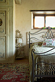 Metallbett mit gemusterten Kissen im Schlafzimmer mit orientalischem Teppich