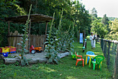 Woman with toddler in the play area in the garden with toys and colourful children's chairs