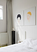 Minimalist bedroom with portrait paintings above the bed