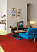 Living room with blue sofa and carpets in red and blue