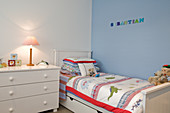 Child's bedroom with white, rustic furniture against blue-painted wall