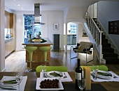 Set table and bar stools at free-standing kitchen island in open-plan, modernised living space