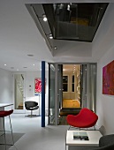 Pinkfarbener Sessel im weissen offenen Wohnraum mit Oberlicht