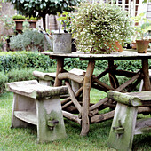 Rustikale Holzgarnitur mit Blütenpflanze im Garten