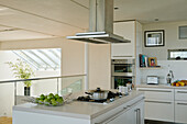 White kitchen with cooking island, built-in appliances and skylights