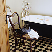 Bathroom with black and white chequered tiles and free-standing bathtub