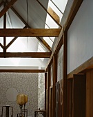 Wooden roof structure and antique standard lamps with balloon-shaped shades in front of intricate, planar, vertical wire sculpture with oval aperture