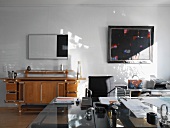 Mix of styles in study with modern steel and glass furniture and retro beech sideboard