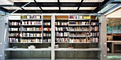 Two-storey concrete bookcase with sliding shelf units at front and gallery level in open steel and wood structure