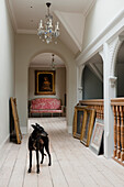 Classic-style hallway with artwork and wooden banister, dog in the foreground