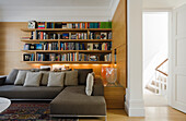 Wohnzimmer mit Bücherregalen, eingebauter Beleuchtung und großem Ecksofa