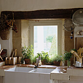 Rustic kitchen with ceramic sink, herb pots and wooden beams