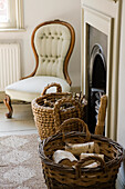 Upholstered armchair in living room next to woven baskets with firewood