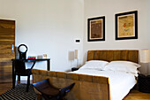 Bedroom with wooden desk, brown upholstered bed and framed art prints on the wall