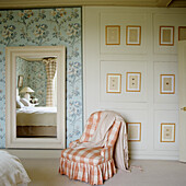 Vintage armchair with chequered upholstery, wall with floral pattern and large mirror