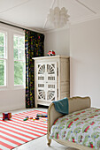 Children's room with vintage wardrobe, striped carpet and toys on the floor