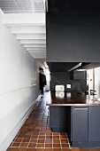 View of tiled corridor & open-plan, black kitchen