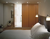 A bedroom with a floor-to-ceiling mirror and an en suite bathroom
