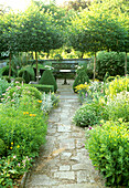 Garden path with natural stone slabs, surrounded by flowering shrub beds