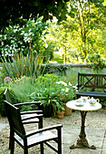 Seating area in the garden with tea service and flowering perennials in summer