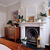 Fireplace with white mantelpiece, orchids and golden lantern