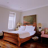 Bedroom with wooden bed, lamps and paintings