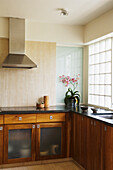 Kitchen unit with wooden furniture and black stone worktop, orchid on worktop