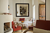 Cosy corner with fireplace, bench with cushions and large wall mirror