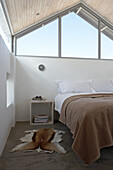 Bedroom with gabled roof, cowhide rug and minimalist bedside table