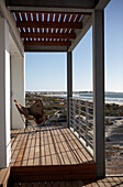 Balcony with wooden floor and steel structure, view of dune landscape