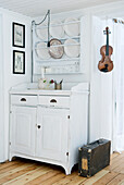 Zimmer im Landhausstil mit weißer Vintage-Kommode, Geschirr-Regal und Geige