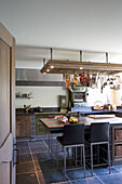 Rustic kitchen with metro tiles and hanging rack for cooking utensils