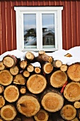 Snow-covered log pile in front of house