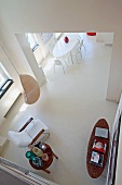 Blick von oben in offenes Wohnzimmer mit Sessel im Fiftiesstil und moderner Essplatz hinter Durchgang