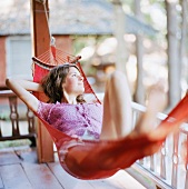 Young woman lying in hammock on terrace